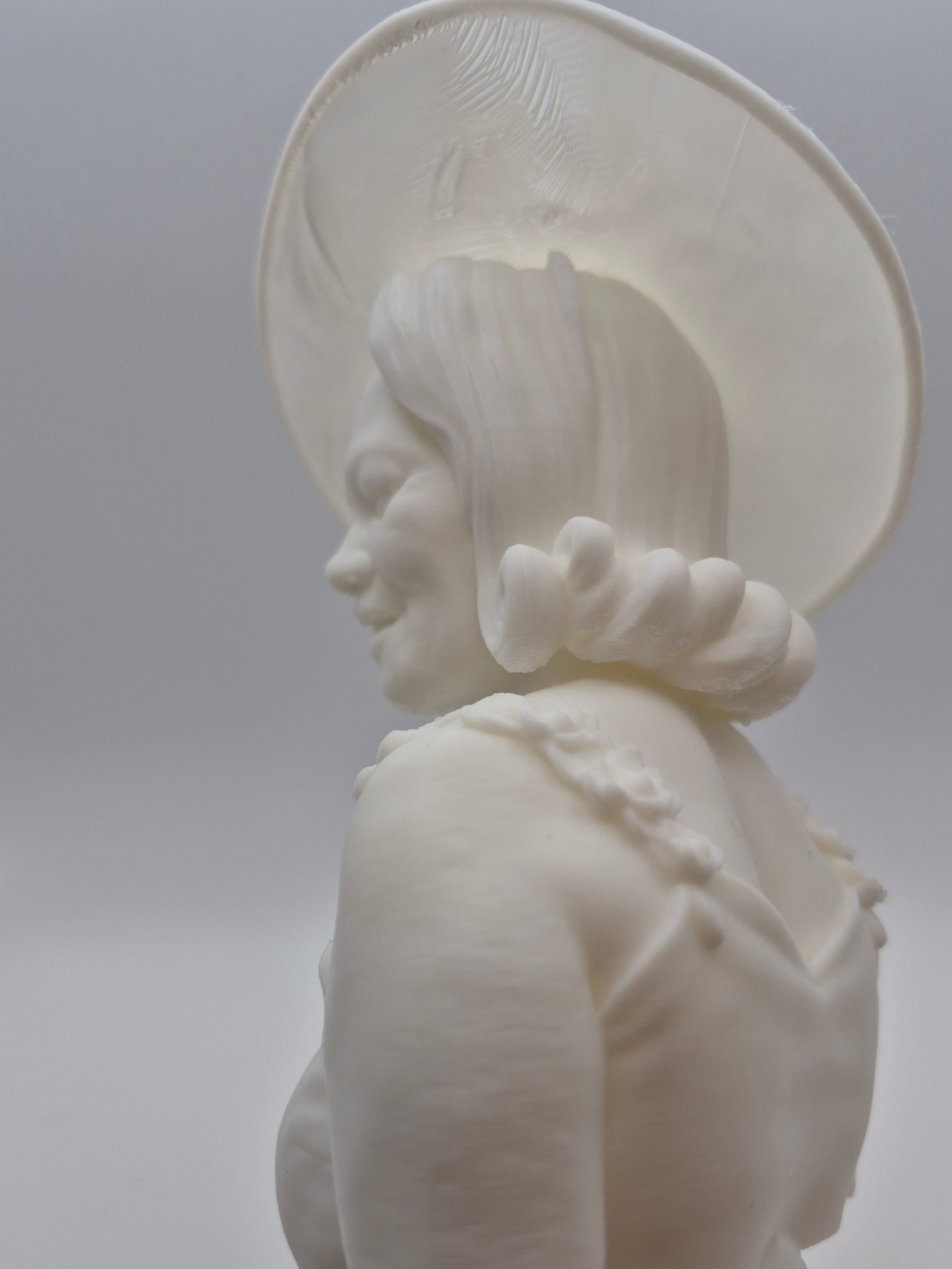 White ceramic sculpture of a face on a plain background