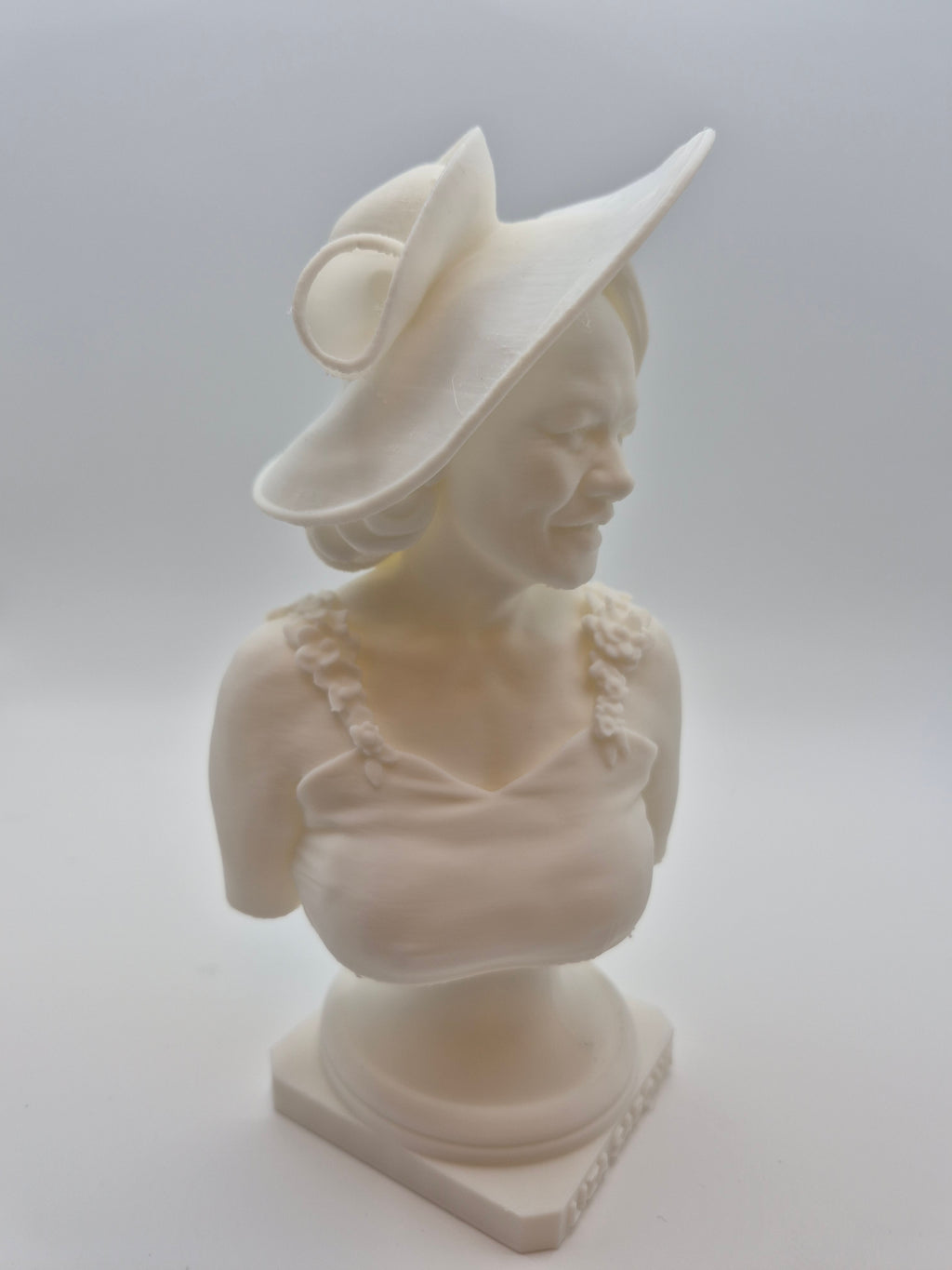White sculpture of a classical figure on a plain background