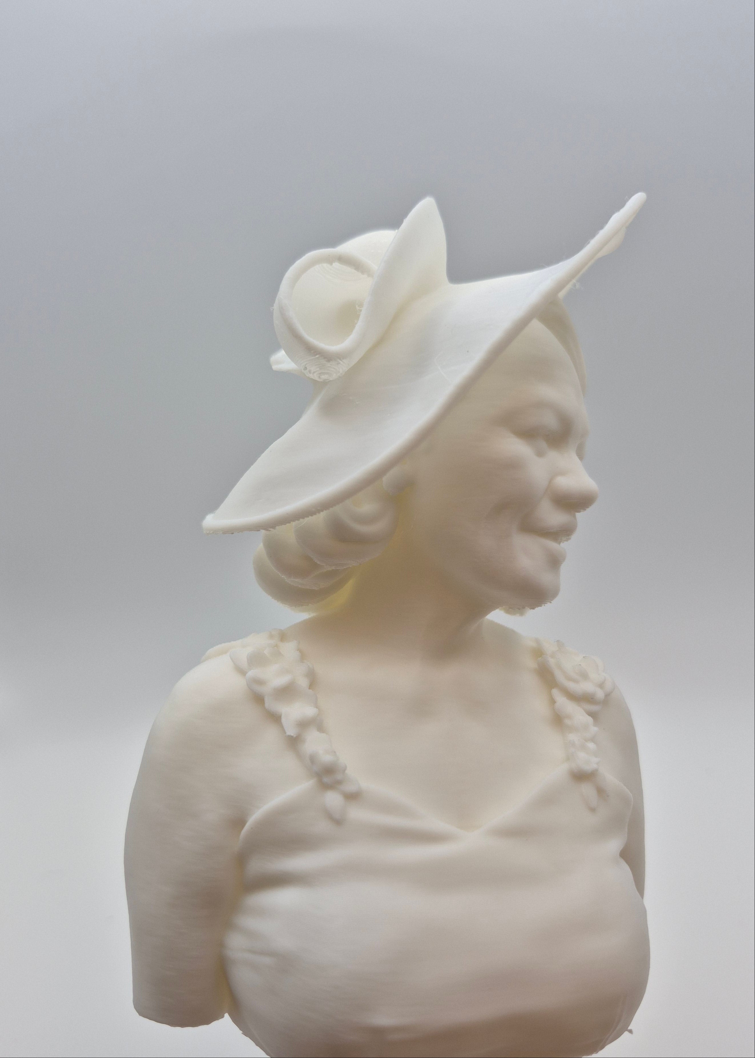 White ceramic bust of a woman wearing a hat on a white background